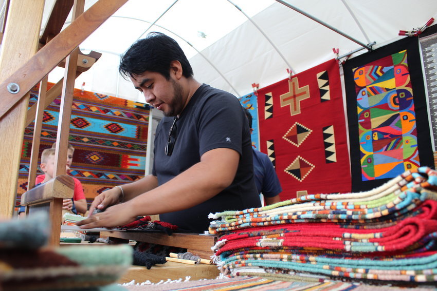 Angel Mendez works at the loom in his uncle's booth during the Golden Fine Arts Festival Aug. 20 in downtown Golden. Zapotec weaver Mel Mendez of Prescott, Arizona was this year's featured artist as the festival's posters and T-shirts featured his rug titled "Contemporary Fish."